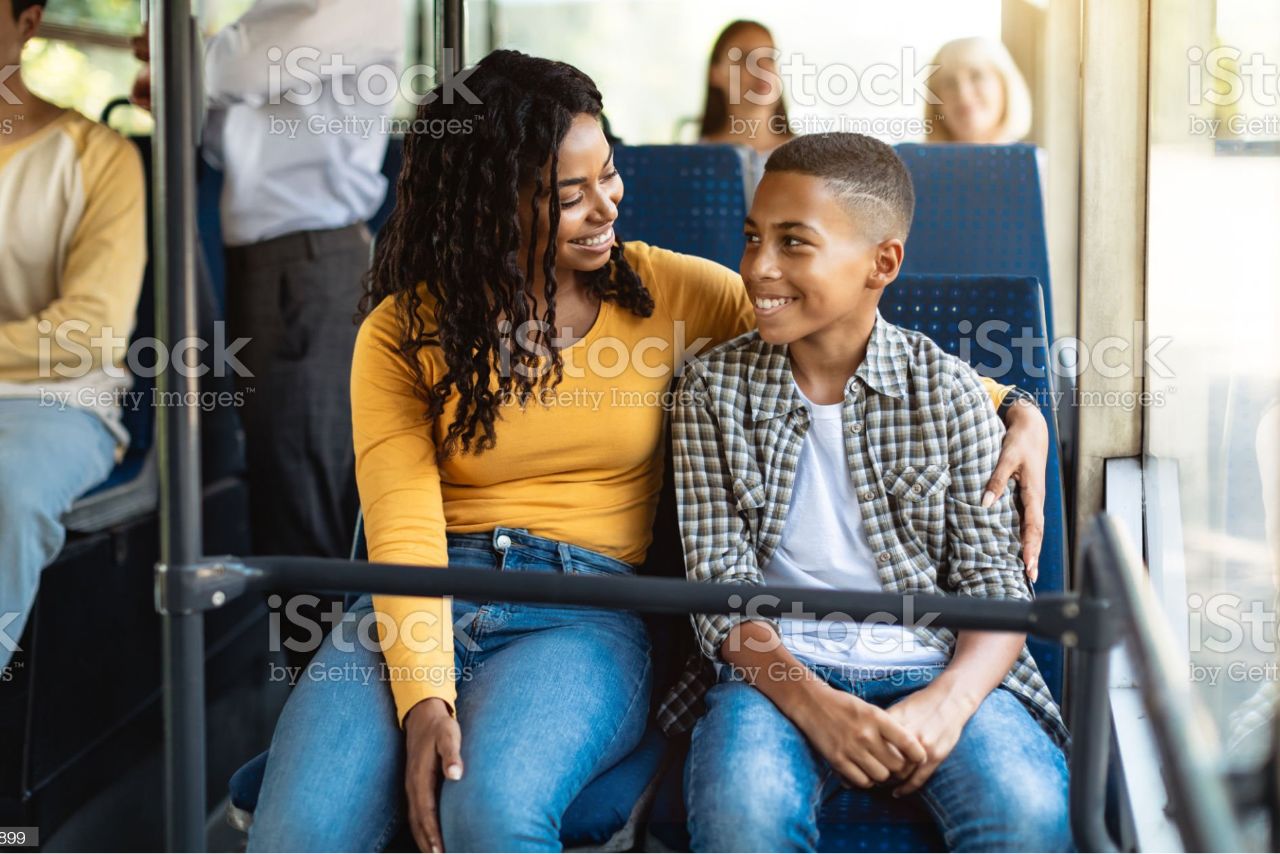 Mother and middle school aged child sit together while riding bus.