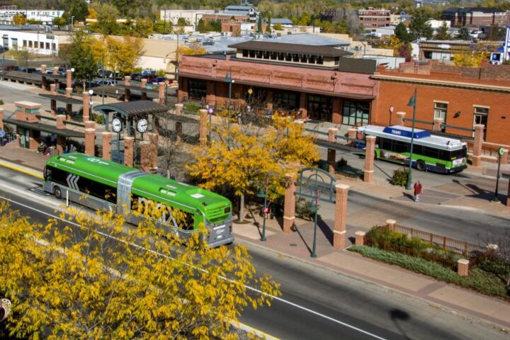 green bus outside of bus station on a fall day