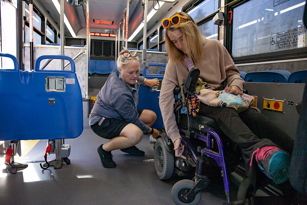 woman helping another woman in a wheelchair board the bus