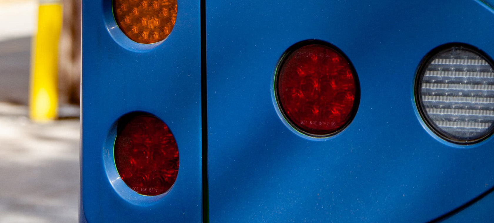 A close up view of a blue bus and its tail lights. 
