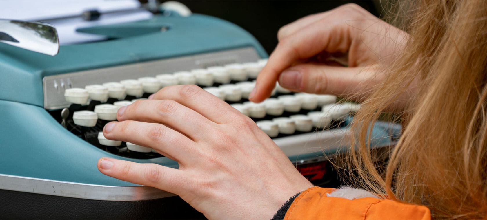 Close up of a woman's hands typing on an antique typewriter. 