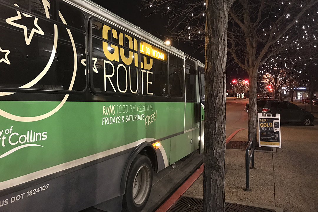 A bus sits next to the curb in Fort Collins at night.