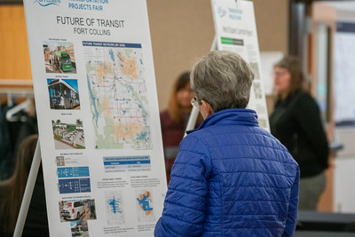 A woman views a transit map on an easel at a public event. 